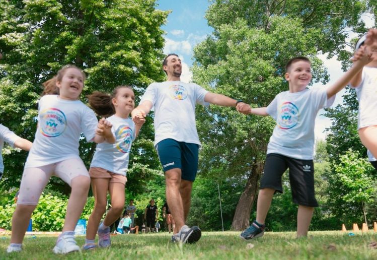Group of joyful children playing outdoors with an instructor in a sunny park.
